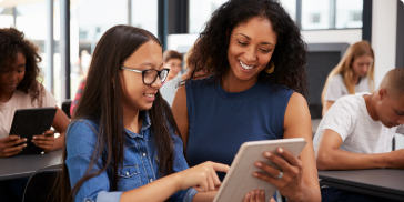 A group of students at a table using a tablet for college readiness planning.