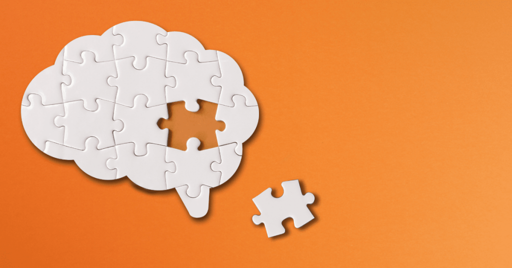 Brain shaped white jigsaw puzzle on orange background, a missing piece of the brain puzzle.