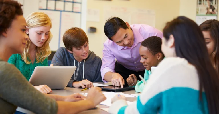 A teacher works with a group of high school students in a small group instructional setting.