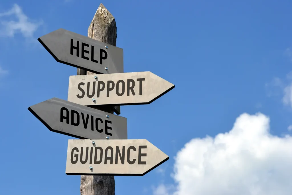 A guide post with several signs pointing in different directions stands against a clear blue sky