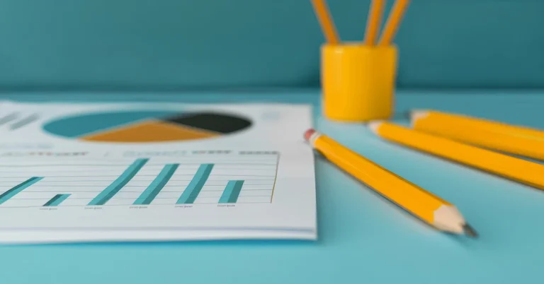 A student data report sits on a turquoise desk next to some yellow pencils.