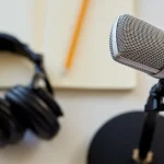 Headphones, a microphone and notebook with pencil on white background