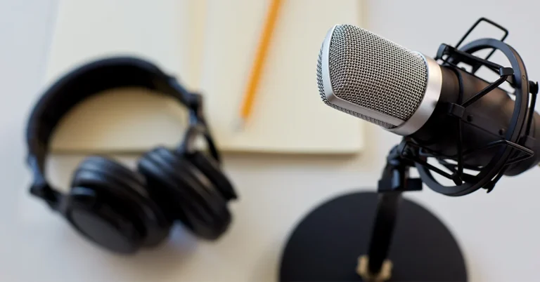 Headphones, a microphone and notebook with pencil on white background
