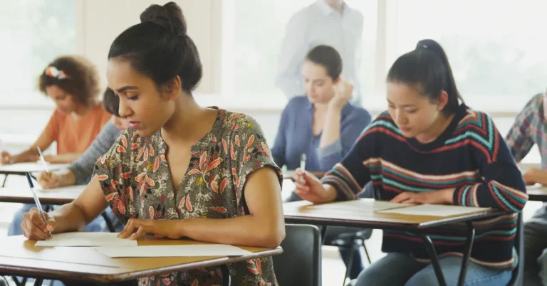 A student sits at her desk, taking a PSAT exam, surrounded by classmates.